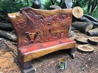 a bench made out of logs in a wooded area