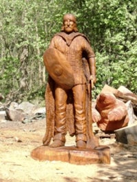 a wooden statue of a man holding a shield