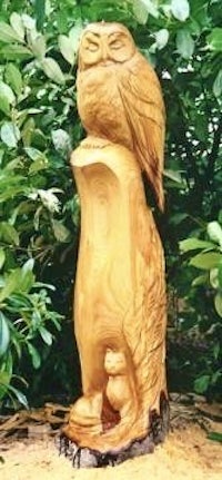 a wood carving of an owl sitting on a tree stump