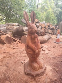 a wooden statue of a rabbit in a wooded area