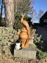 a cat sits next to a statue of a peacock