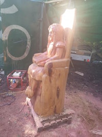 a wooden statue of a woman sitting in a chair