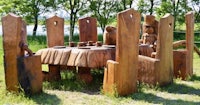 a wooden table with chairs in the middle of a grassy field