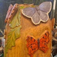 a tree stump with butterflies and leaves on it