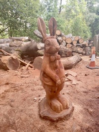 a wooden statue of a rabbit in a wooded area