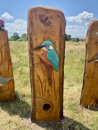 three wooden carvings with birds and butterflies on them