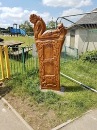 a wooden sculpture in a park with a fence around it