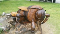 a wooden sculpture of a bee sitting on top of a log