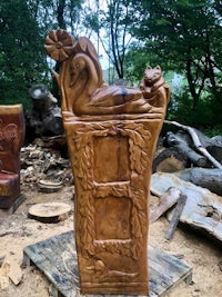 a wooden carving of a cat and a swan