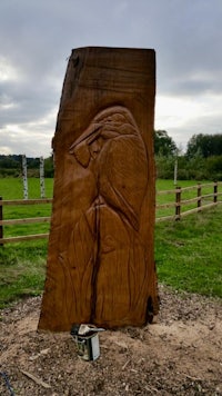 a wooden carving of a bird in a field