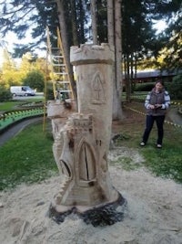 a man is standing next to a sand castle