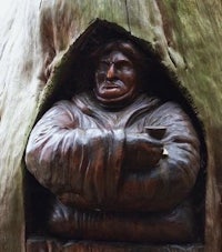 a statue of a man in a tree trunk