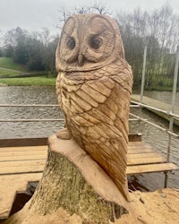 a wood carving of an owl sitting on top of a tree stump