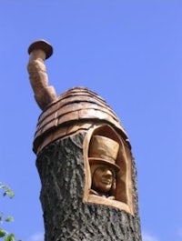 a tree trunk with a carving of a man in a hat