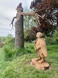 a statue of a boy standing next to a tree