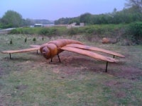 a wooden sculpture of a bug in a field