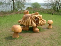 a wooden sculpture of a mushroom sitting in a grassy area