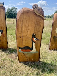 three wooden carvings of birds in a field