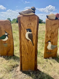 three wooden carvings of birds in a field