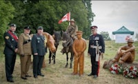 a group of men in uniform standing next to a statue of a canadian soldier