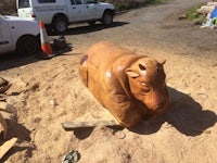 a wooden sculpture of a cow in the sand