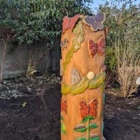 a wooden sculpture with butterflies on it in a garden