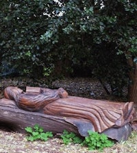 a statue of a woman laying on a log in the woods