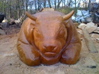 a wooden sculpture of a bull in the woods