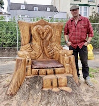 a man standing next to a tree stump with a carved throne