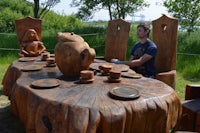 a man sits at a table made from a tree stump