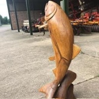 a wooden fish sculpture in front of a building