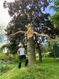 a man standing next to a tree with a tree carving