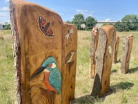 a group of wood carvings in a field with birds on them