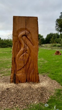 a wooden sculpture of a heron in a park