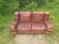 a couch made out of wood in the middle of a field