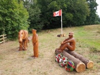 a group of wooden statues in a field with a canadian flag