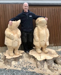 a man standing next to two wooden statues