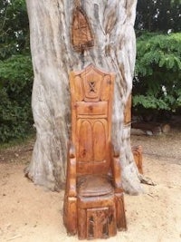 a wooden throne in front of a tree