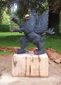 a black statue of a griffin on top of a log