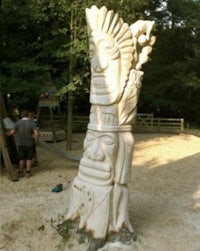 a statue of a tiki in a wooded area