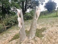 a pair of wooden sculptures in a field