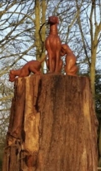 a statue of a dog on top of a tree stump