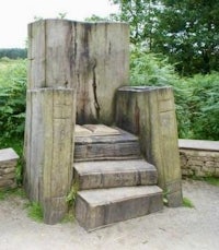 a wooden throne in the middle of a field