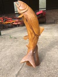 a wooden fish sculpture in front of a barn