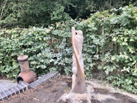 a wooden sculpture in a garden next to a fire pit