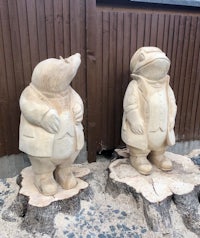 two wooden statues of a man and a frog