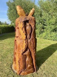 a carved tree stump in the middle of a grassy area