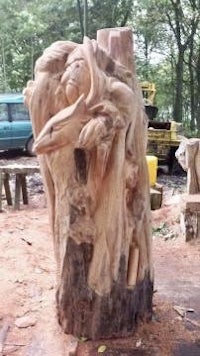 a man carving a tree stump in the woods