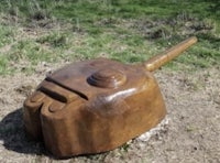 a wooden tank sitting on the ground in a field