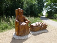 a wooden statue of a man and a woman sitting on a throne